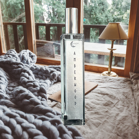 Amberwood room spray bottle in a cozy bedroom with warm lighting and soft textures, styled to evoke a calm, comforting atmosphere.